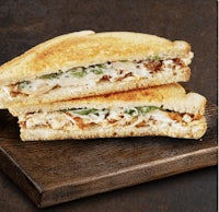 two grilled chicken sandwiches on a wooden board