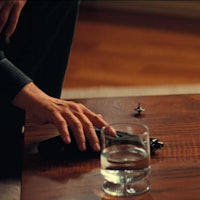 a man's hand on a table with a glass of water