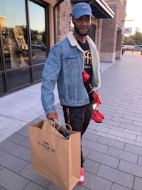 a man in a denim jacket holding a shopping bag