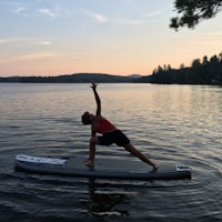 a woman doing yoga on a stand up paddle board