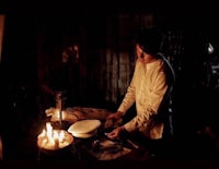 a man in a white shirt is preparing food in a dark room