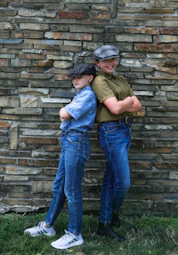 two children posing in front of a stone wall
