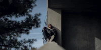 a man sitting on the edge of a concrete wall