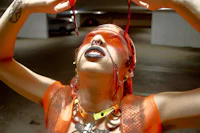 a woman in an orange outfit is holding her head up in a parking garage