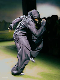 a man in black doing a stunt on a skateboard