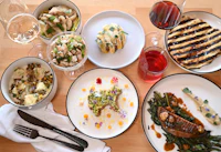 a table with plates of food and wine on a wooden table