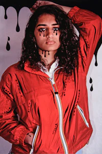 a woman wearing a red jacket with dripping eyes