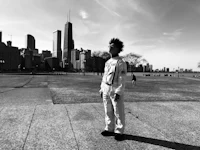 a black and white photo of a man standing in front of a chicago skyline