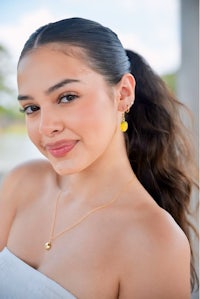 a young woman wearing a yellow necklace and earrings