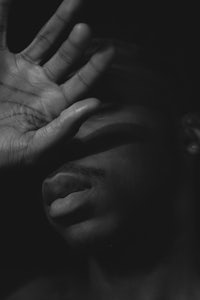 a black and white photo of a man with his hand over his face