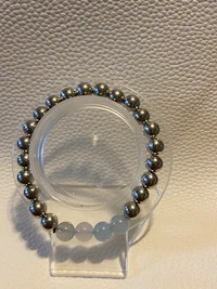 a bracelet with silver beads on a white surface