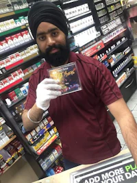 a man in a turban holding a cd in front of a store