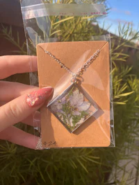a person holding a necklace with a flower in it