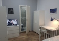 a small bedroom with a bed, desk and tv