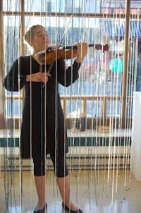 a woman playing a violin in front of a curtain