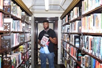 a man standing in a library holding a book