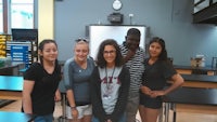 a group of young people posing for a picture in a classroom