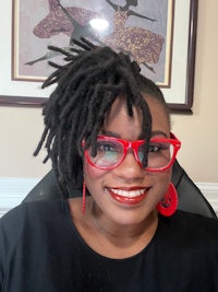 a woman with dreadlocks wearing red glasses