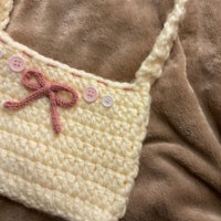 a crocheted bag with a pink bow on it