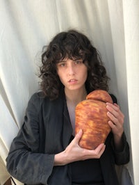 a woman with curly hair holding a bread