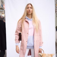 a woman in a pink coat with a dog standing next to her