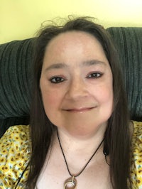 a woman sitting on a couch with a necklace on her neck