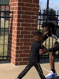 a man in a black shirt is holding a young boy's hand