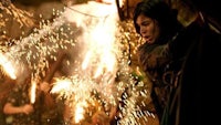 a woman holding a sparkler in front of a crowd of people