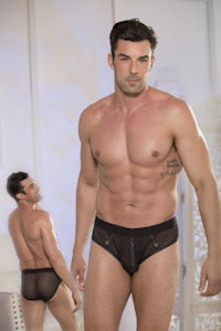 a man is standing next to another man in a black brief