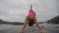 a woman doing a handstand on a paddle board