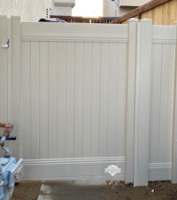 a white fence in a backyard with a water hose
