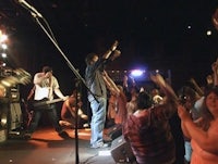 a group of people on stage with their hands raised in the air