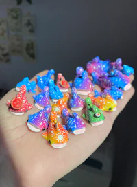 a person's hand holding a bunch of colorful fish figurines