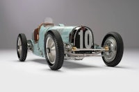 a vintage racing car is shown on a grey background