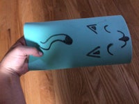 a person holding up a piece of paper with a cat face on it