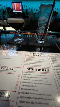 a menu with drinks and sushi rolls on a table