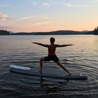 a woman standing on a surfboard in a body of water