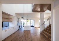 a white kitchen with wooden floors and stairs
