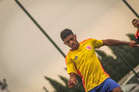 a man in a yellow shirt is kicking a soccer ball
