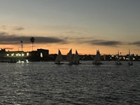 a group of sailboats on a body of water at sunset
