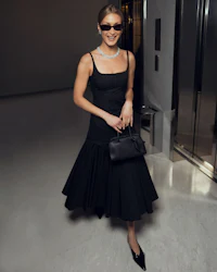 a woman wearing a black dress and sunglasses is standing in an elevator