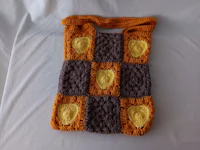 an orange and grey crocheted bag on a bed