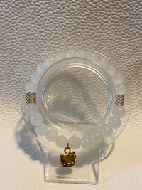 a white beaded bracelet with a gold plated clasp