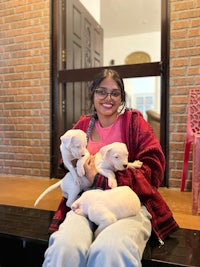 a woman sitting on a bench with two puppies
