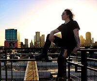 a man sitting on a railing with a guitar