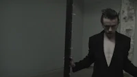 a man in a black suit standing next to a pole