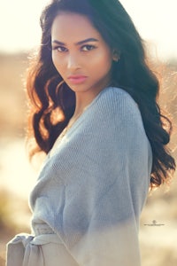 a young woman in a gray sweater posing for a photo
