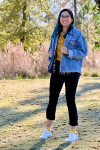 a woman in a denim jacket standing in a field