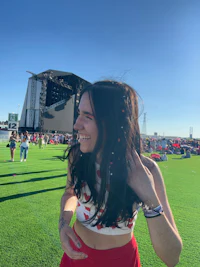 a woman smiling in front of a stage at a music festival