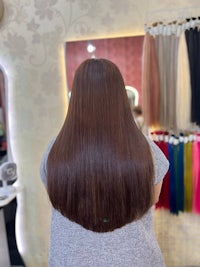 the back of a woman with long brown hair in a salon